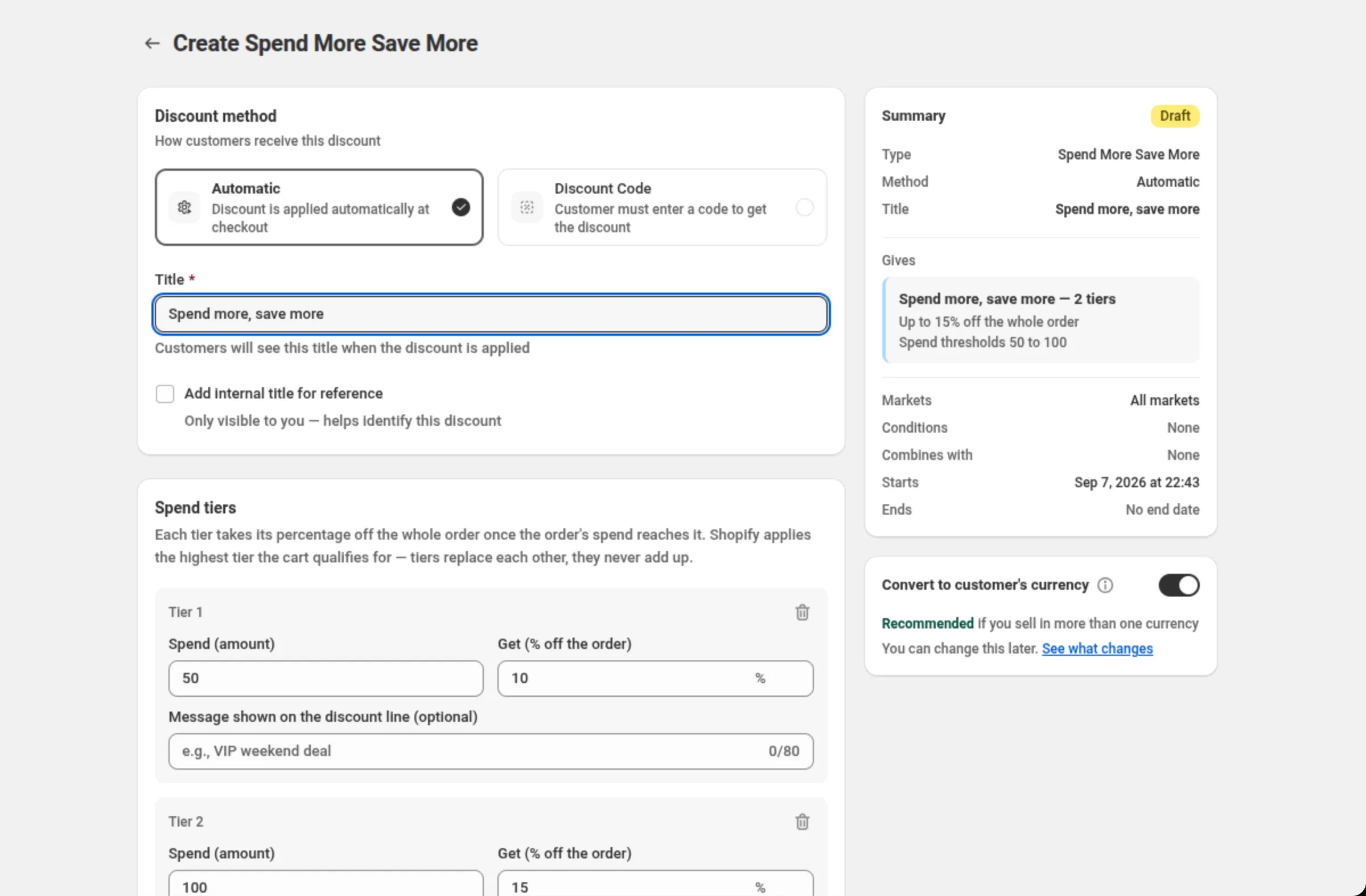 The Create Spend More Save More page with the Title field reading Spend more, save more, the Spend tiers card showing Tier 1 at spend 50 for 10% and Tier 2 at spend 100 for 15%, each with a Message shown on the discount line field, and the Summary and Convert to customer's currency cards on the right